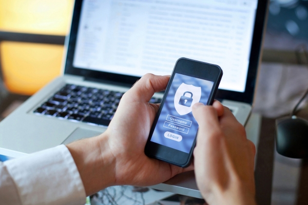 Accesso sicuro e verifica dell'identità cliente: un utente utilizza il proprio smartphone per un login protetto con simboli di sicurezza
