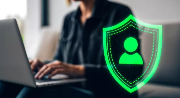 Persona davanti al PC con shield icon per  sicurezza del Digital Onboarding